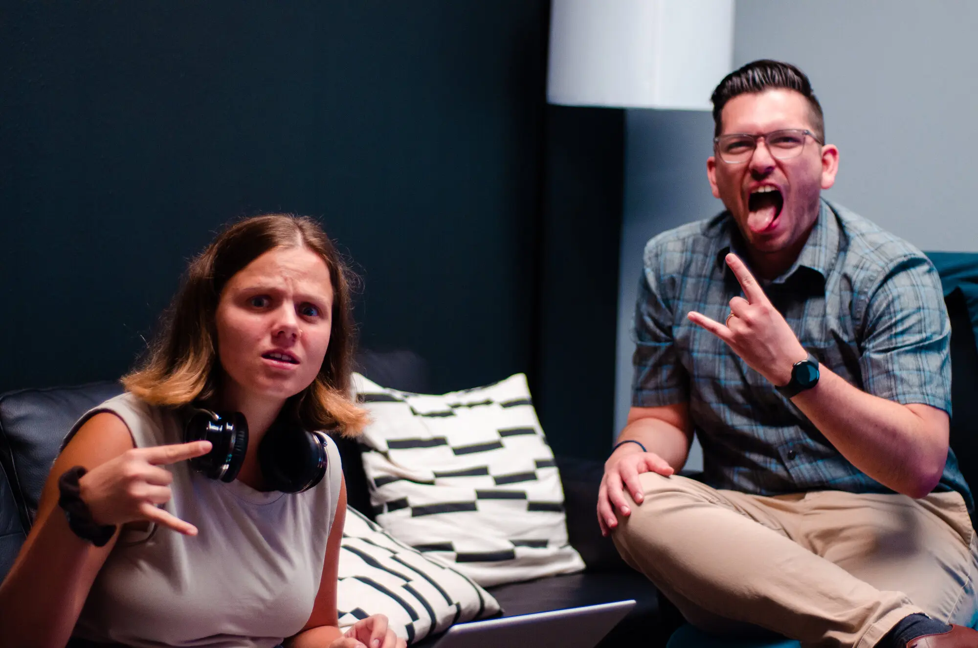 Two teammates on a couch pulling exaggerated rock-on faces at the camera.