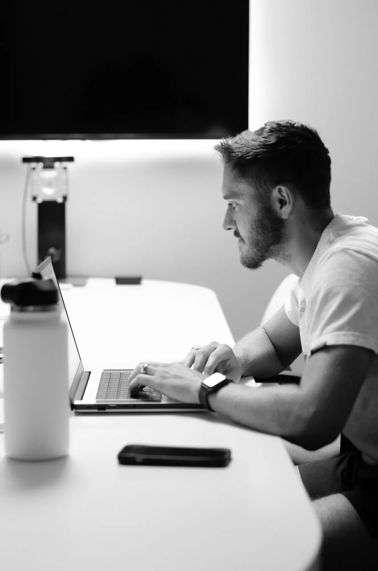 Black-and-white photo of a developer working at a laptop in a quiet office.