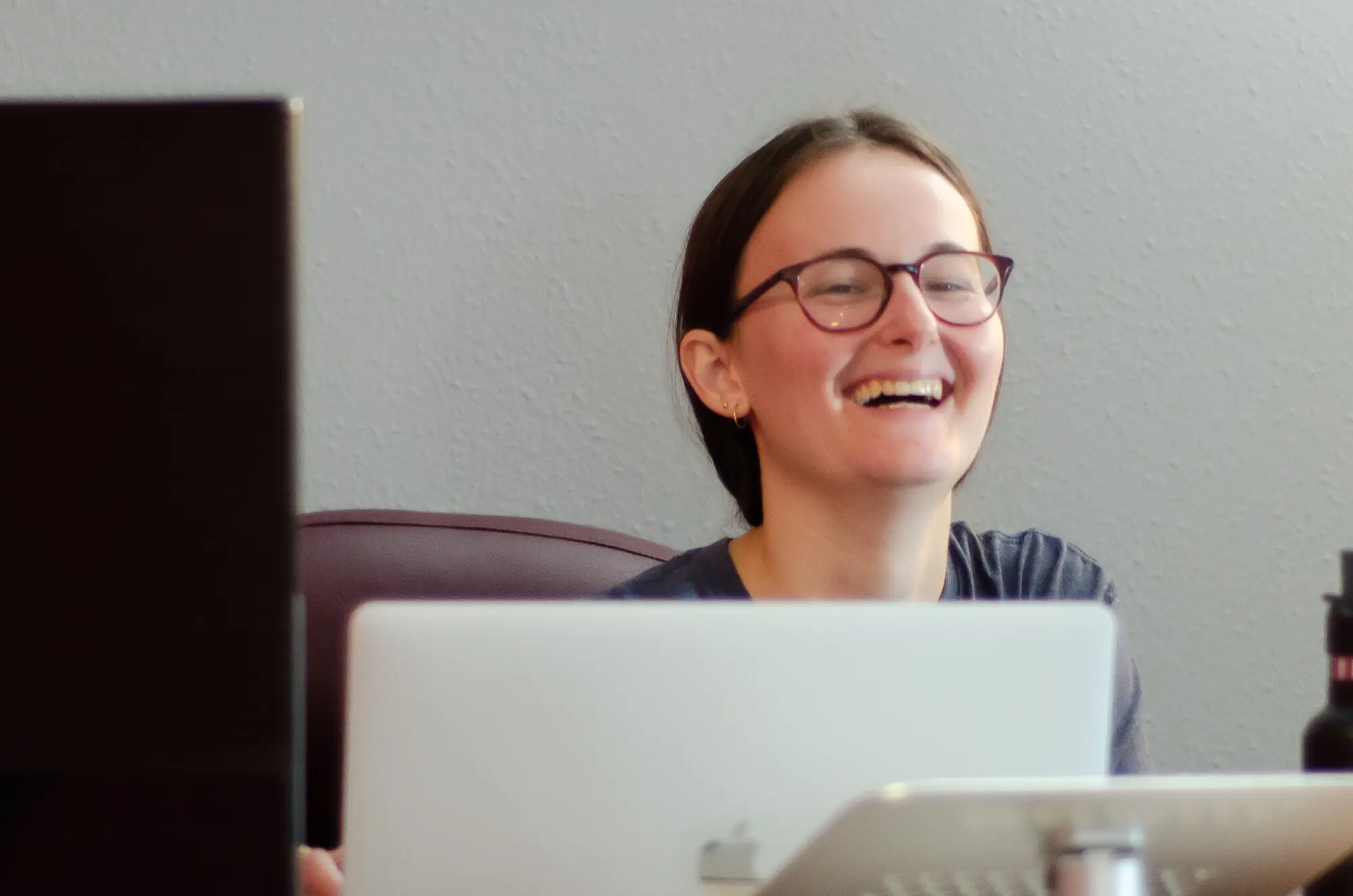 A QREW team member laughing while working at her laptop.