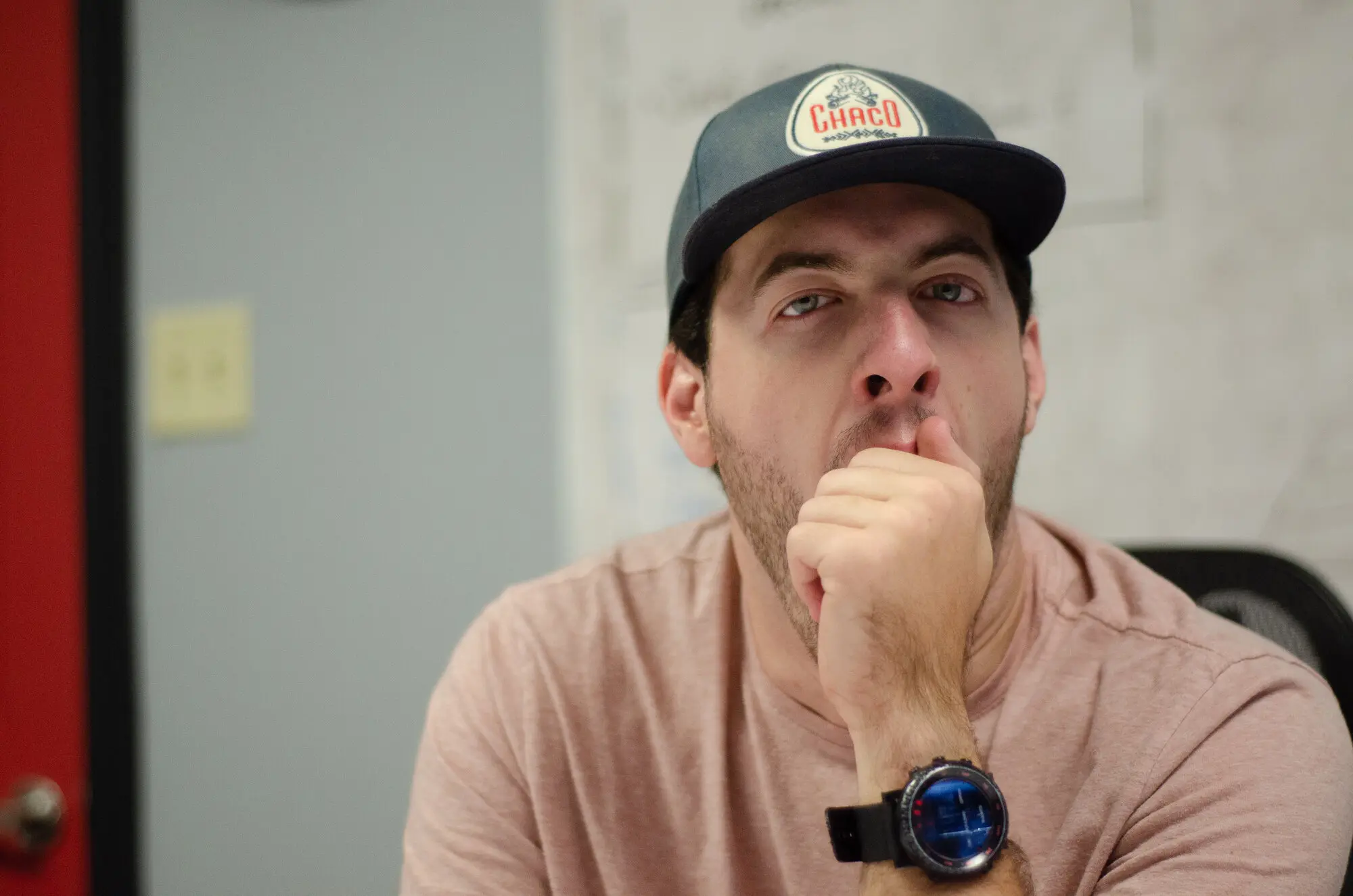 A QREW presenter on camera, hand to chin, mid-thought.