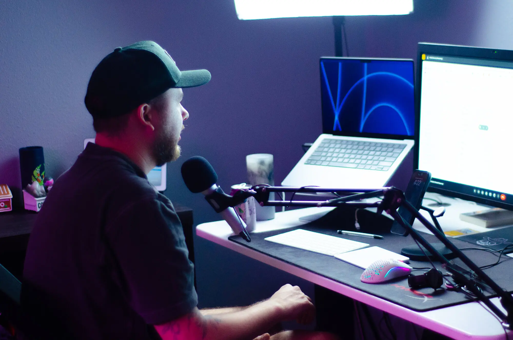 A team member at a desk mic with dual monitors, recording a tutorial.